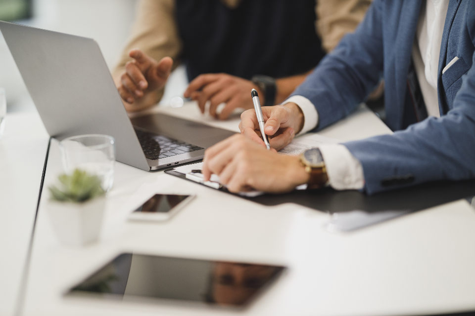 Two people reviewing paperwork at a desk with a laptop